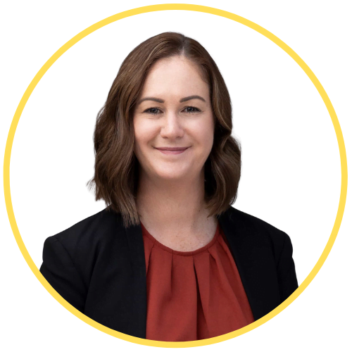 About 7 Portrait of a woman with shoulder-length brown hair, wearing a black blazer and a rust-colored blouse, smiling at the camera. The image is enclosed in a yellow circular border.