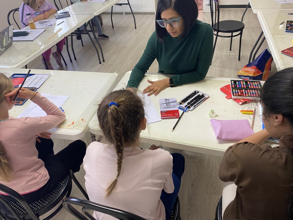 An art tutor guiding children through a drawing exercise